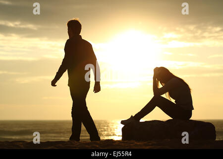 Couple silhouette breaking up a relation on the beach at sunset