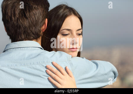 Sad woman hugging her boyfriend and looking down couple problems concept Stock Photo