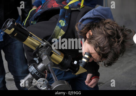a boy is looking through an amateur telescope to observe the solar eclipse through the lens Barcelona Stock Photo