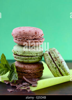 Chocolate and mint flavor macaroons on dark wood table and green background. Stock Photo