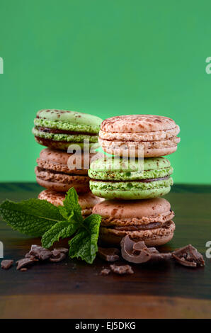 Chocolate and mint flavor macaroons on dark wood table and green background. Stock Photo