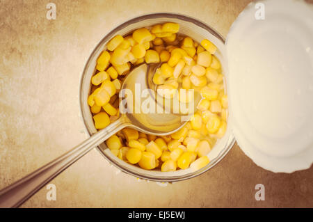 Sweet corn in an open tin can with a spoon. Top view Stock Photo