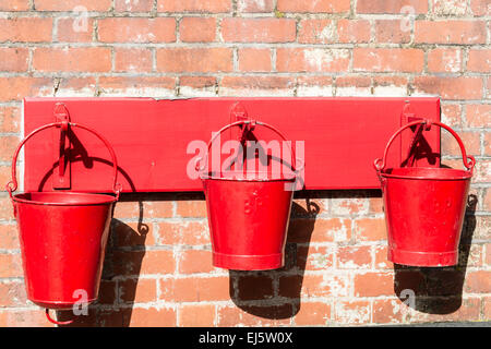 Three old fire buckets hanging on a wall Stock Photo
