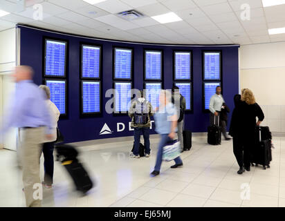 Airport passengers view airport departure boards inside airport terminal while traveling Stock Photo