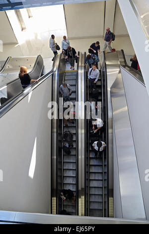 Passengers travel through airport on airport escalator through airport terminal Stock Photo