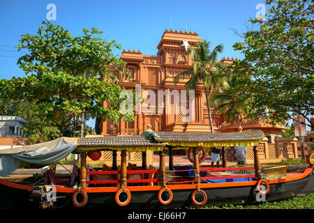 Traditional Indian boat with historic building at background in Allepey, Kerala Stock Photo