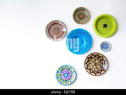 Concept of colorful decorative plates hanging on white wall Stock Photo