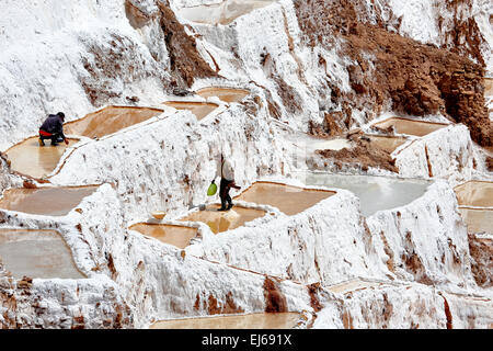 Salt pans and men collecting salt, Salineras (salt mines), Cusco, Peru Stock Photo