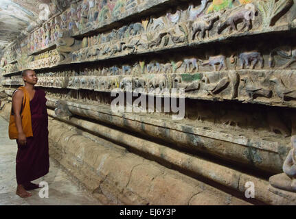 Monk looking at stone carving in Shitthaung Temple, Mrauk-U, Rakhine State, Myanmar Stock Photo