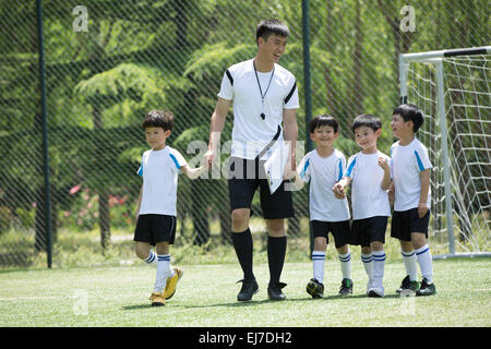 The football coach and the boys walking in the football field Stock Photo