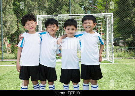 The four boys hug the shoulder on the football field Stock Photo