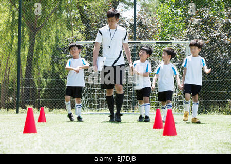 The football coach and the boys walking in the football field Stock Photo