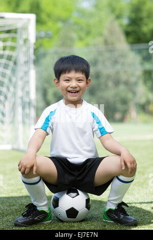 The boy excited sat on football Stock Photo