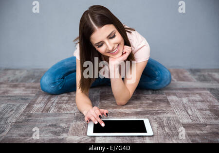 Young happy woman sitting on the floor and using tablet computer Stock Photo