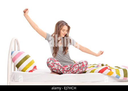 Beautiful woman waking up in the morning and stretching seated on a bed isolated on white background Stock Photo
