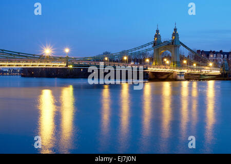Long exposure side shot of Hammersmith Bridge, in West London, over the river Thames at dusk. Stock Photo
