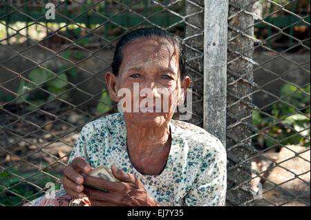 An old Burmese lady holding some money in her hands begging on a Rangoon street Myanmar Burma Stock Photo