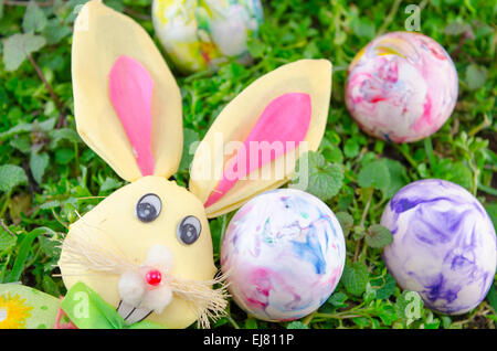 Easter bunny puppet and a water colored egg lying on the grass Stock Photo