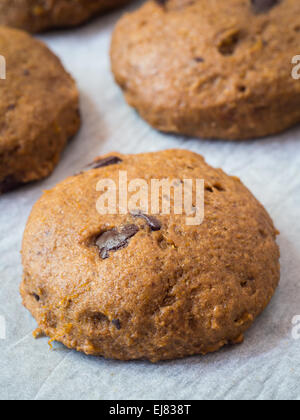 Vertical photo of whole grain vegan soft spelt pumpkin cookies with chocolate chips on a piece of baking paper. Close up. Stock Photo