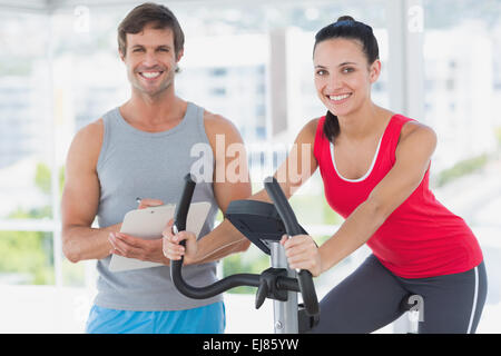Woman with instructor working out at spinning class in bright gym Stock Photo