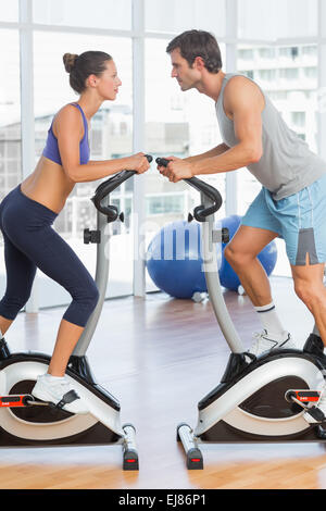 Side view of a couple working at spinning class in gym Stock Photo