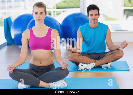 Young couple sitting in lotus posture at fitness studio Stock Photo