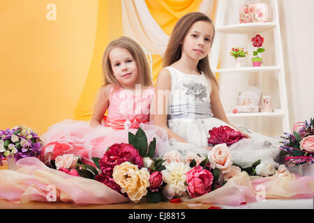 Pretty twins posing with flowers in studio Stock Photo