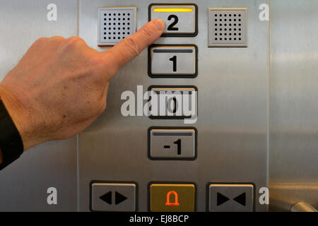 Finger presses button second floor Stock Photo