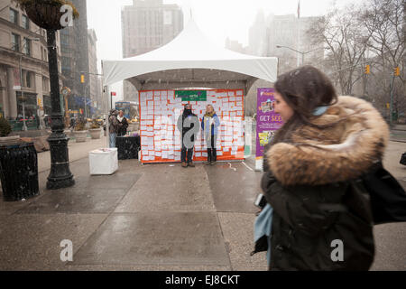 New Yorkers and visitors celebrate the Workers try to attract passer-by to their booth in Madison Square in New York to celebrate the United Nations International Day of Happiness by writing how they will share their happiness, on Friday, March 20, 2015. The festive day, which shares the date with the first day of Spring, was celebrated by Mother Nature with a snowstorm predicted to drop several inches of snow on an unhappy populace tired of the snow and winter. (© Richard B. Levine) Stock Photo