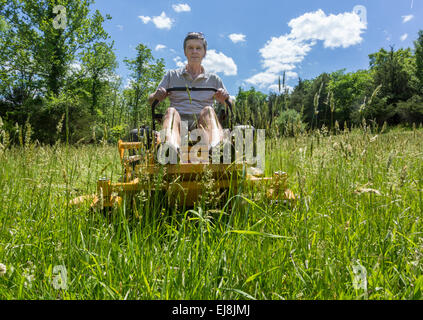 Senior man on zero turn lawnmower in meadow Stock Photo