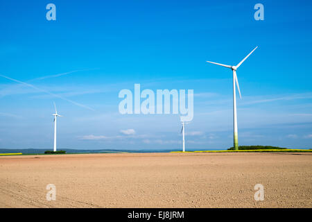 Windwheels behind a barren field Stock Photo