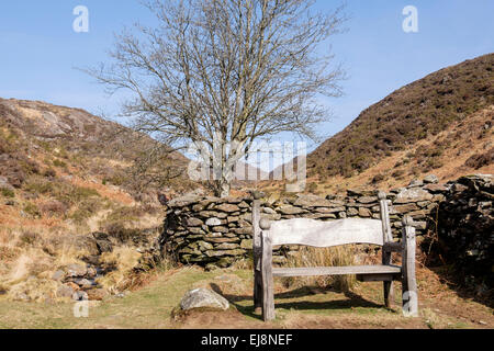 Empty wooden memorial bench seat with inscription in Cwm Bychan in Snowdonia National Park near Beddgelert, Gwynedd, Wales, UK Stock Photo