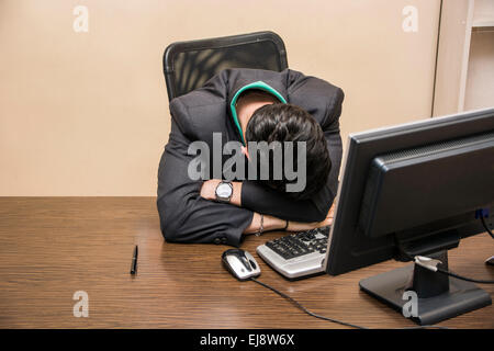 Overworked, tired young businessman sleeping on his desk  in office, in front of computer Stock Photo