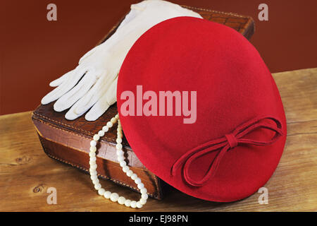 Red hat, white gloves and bone beads on leather case Stock Photo