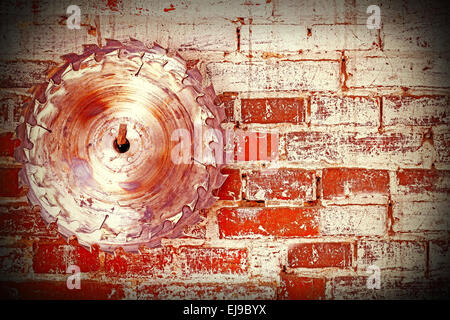 Circular saw blade on a grungy brick wall, background or texture. Stock Photo
