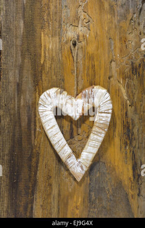 carved wooden heart is hanging on tree bark Stock Photo
