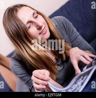 woman reading magazine on sofa Stock Photo