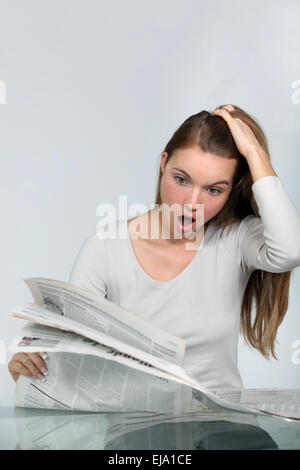 Shocked woman reading a newspaper Stock Photo