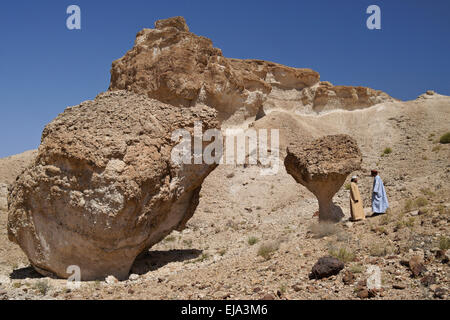 Omani men talking beneath desert mushroom near Mazara, Oman Stock Photo