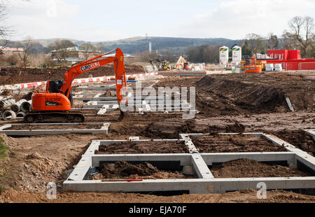 Residential construction site UK with the concrete foundations of rural starter affordable homes.  Digger and mud. Stock Photo