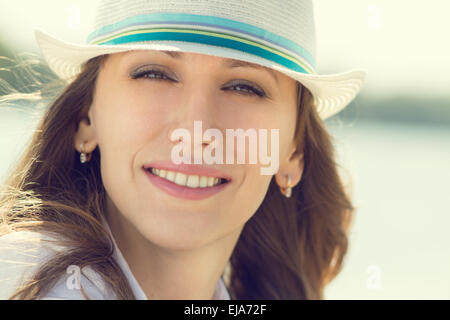 Young smiling hipster woman has fun near sea at summer vacation. Warm color toned image