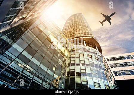 plane flying over modern office tower Stock Photo