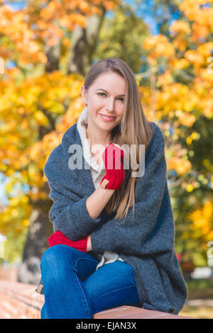 Trendy young woman sitting on a wall Stock Photo