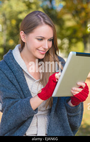 Smiling woman in red mittens using a tablet Stock Photo