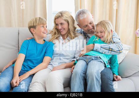 Happy family sitting on couch together Stock Photo