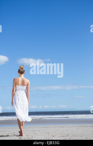 Blonde in white dress walking on the beach smiling at camera Stock ...