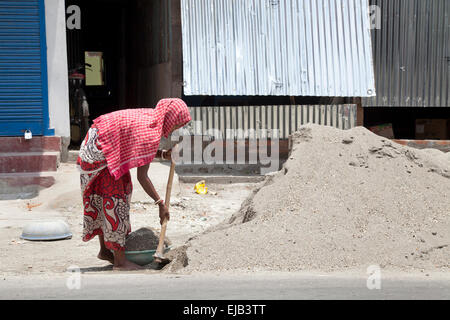 Woman laborer shoveling sand on construction site,  West Bengal, India Stock Photo