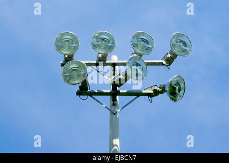 Set of seven stadium floodlights on tower against blue sky. Stock Photo