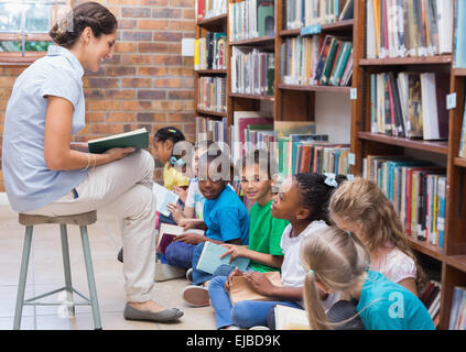 Cute pupils sitting on floor in library Stock Photo