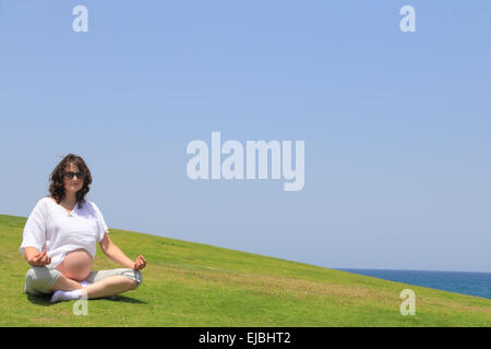 Happy young pregnant woman doing yoga Stock Photo